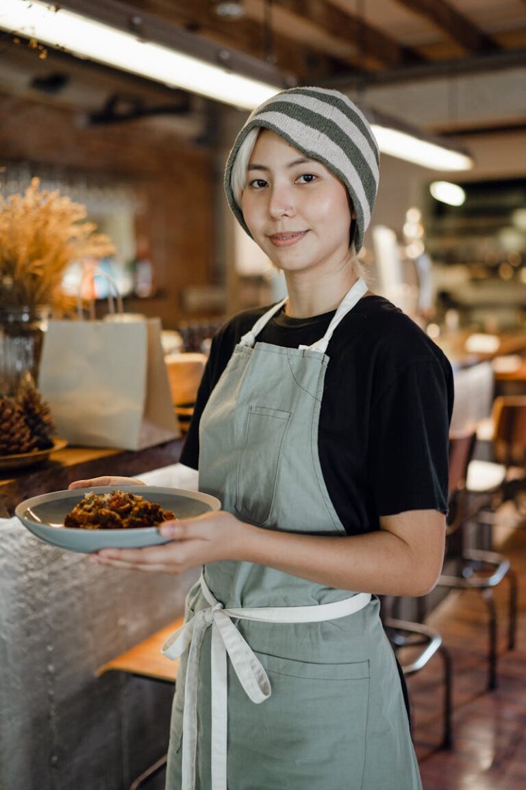 Smiling waitress standing in a cozy café holding a delicious meal, embodying hospitality and service.